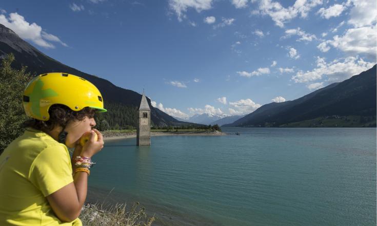 landschaft-reschensee-junge-isst-apfel-vinschgau-tg