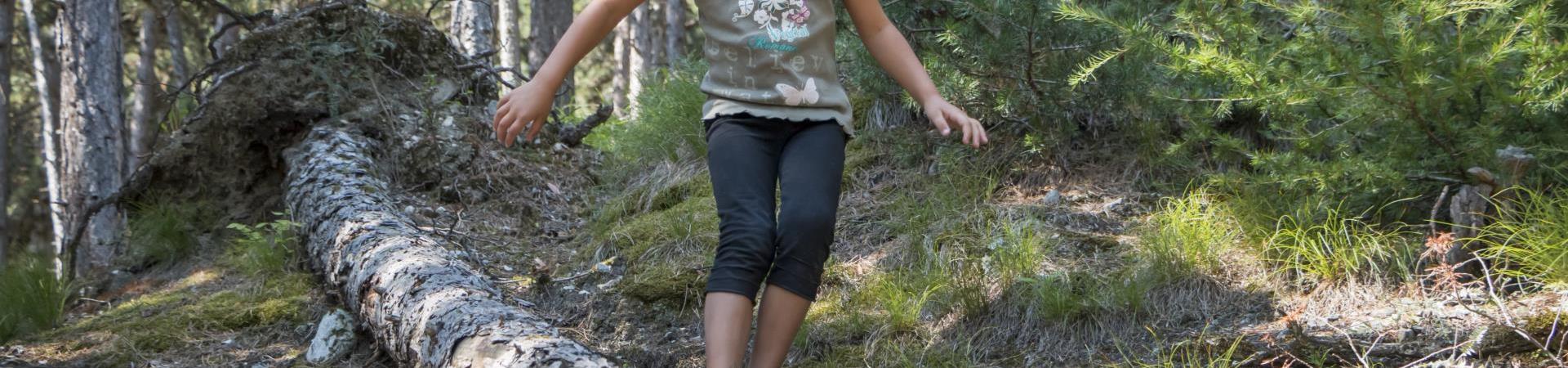 A kid is balancing on a trunk